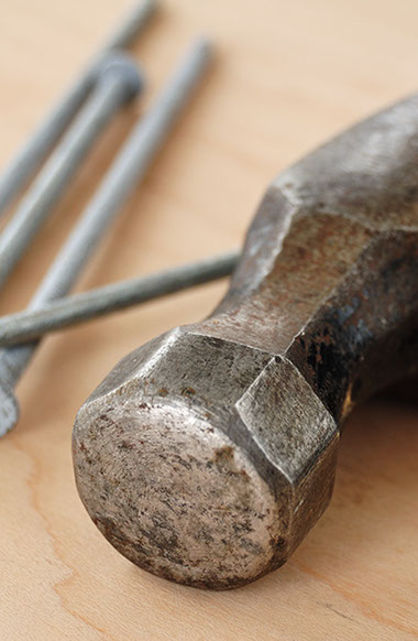 Image of a hammer with nails in the background, Adobe Stock Image.
